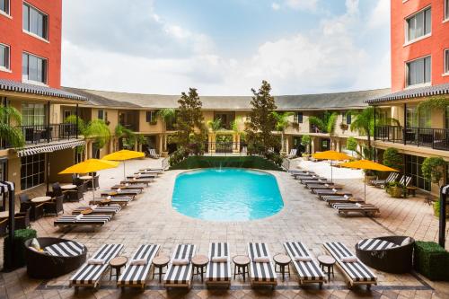 an outdoor swimming pool with lounge chairs and umbrellas at Hotel Zaza Houston Museum District in Houston