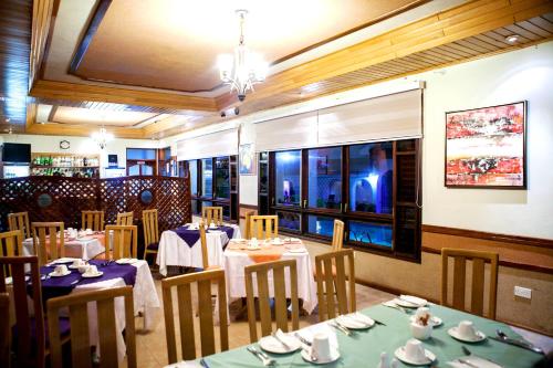 a dining room with tables and chairs with blue tablecloths at Mahogany Lodge, Cantonments in Accra