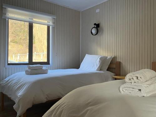 a bedroom with two beds and a window at Cabañas - Casa Rural 32 in Villa O'Higgins