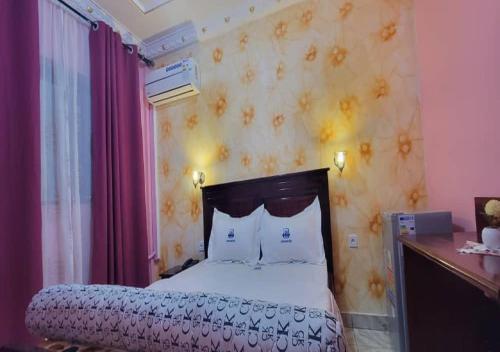 a bedroom with a bed and a wall with flowers at NEFAR PALACE HOTEL Plc in Bafoussam