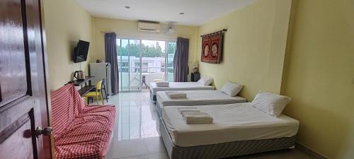 a room with three beds and a tv and a window at Jomtien Hostel in Jomtien Beach