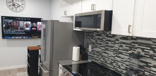 a kitchen with a microwave and a refrigerator and a tv at Executive 1Bedroom Suite By Henday in Edmonton