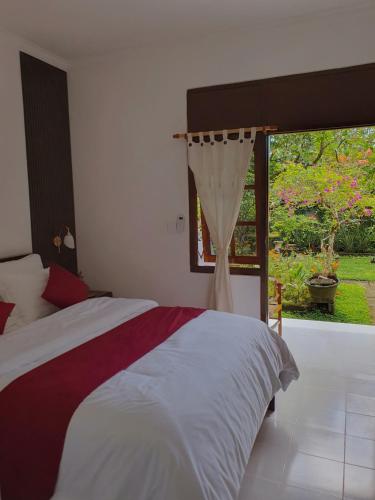 a bedroom with a bed and a large window at GYANA House in Ubud