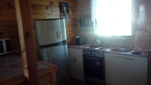 a kitchen with a refrigerator and a sink at Cabañas Sol de Buchupureo in El Cerrillo