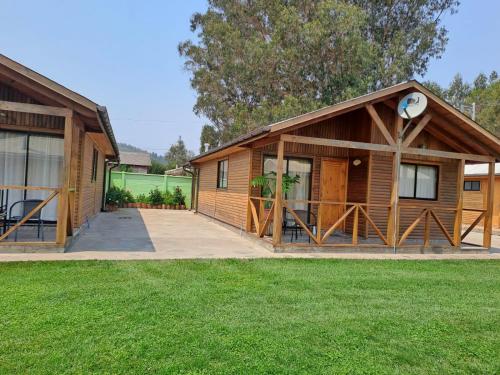 a large wooden house with a grass yard at Cabañas Sol de Buchupureo in El Cerrillo