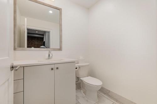Un baño blanco con inodoro y espejo. en The Saddlery - Encore - 1 Block to Broadway, en Nashville