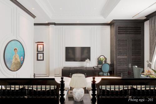 a living room with a table and a television at Indocharm Villa Cat Ba in Cat Ba