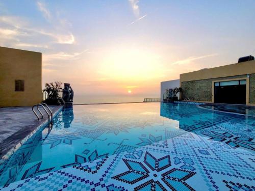 ein Swimmingpool mit einem Sonnenuntergang im Hintergrund in der Unterkunft Apec Boutique Hotel Phú Yên in Phước Hậu (1)