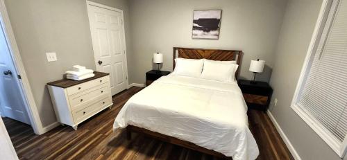 1 dormitorio con 1 cama con sábanas blancas y mesita de noche en Quiet and Comfortable 2 BD Duplex, en Salem