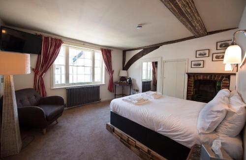 a bedroom with a bed and a chair and a fireplace at Alma Inn & Dining Rooms in Harwich