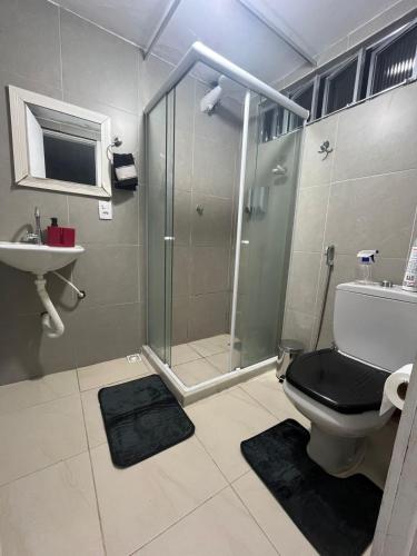 a bathroom with a shower and a toilet and a sink at Quarto de vila na Urca in Rio de Janeiro