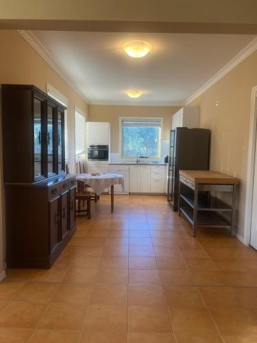 Una cocina con suelo de baldosas, mesa y nevera en Beachside Apartment, en Apollo Bay