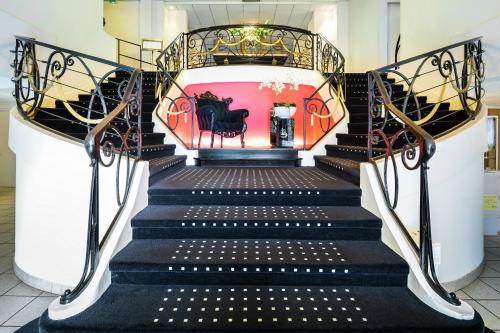 a staircase with black steps and a red wall at Mercure Lourdes Impérial in Lourdes