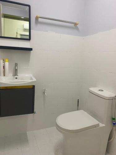 a white bathroom with a toilet and a sink at Cantique Homestay in Mantin