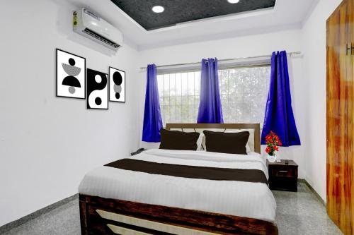 アウランガーバードにあるSuper Townhouse Chhatrapati Shivaji Maharaj Museum Formerly 7 Hillsのベッドルーム1室(青いカーテン付きの大型ベッド1台付)