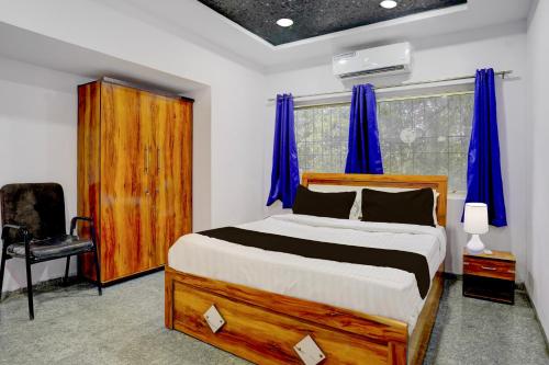 a bedroom with a large bed with blue curtains at Super Townhouse Chhatrapati Shivaji Maharaj Museum Formerly 7 Hills in Aurangabad