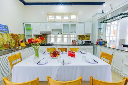 eine weiße Küche mit einem Tisch mit Blumen darauf in der Unterkunft Villa Hồ Bơi Vũng Tàu Đi Bộ Ra Biển - Gần Tháp Tam Thắng - Amy 7 in Vũng Tàu