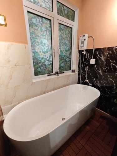 a white bath tub in a bathroom with two windows at HI Studio Mesahill Premier - KLIA - Bathtub - WIFI & NETFLIX in Nilai