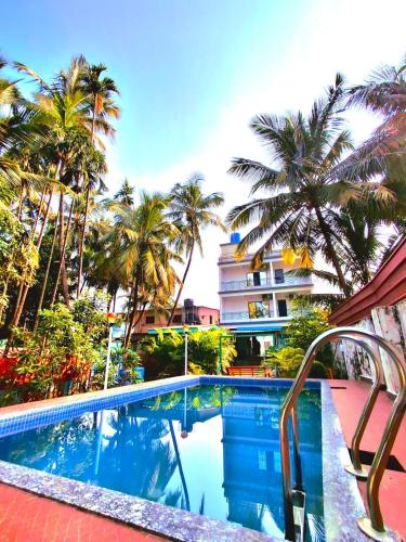 ein Swimmingpool mit Palmen und einem Gebäude in der Unterkunft STARFISH Resort in Nagaon