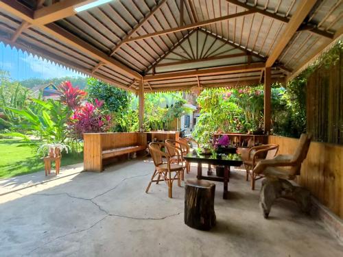 a patio with a table and chairs under a pavilion at Jinghong Manyun Dai Village Inn in Jinghong