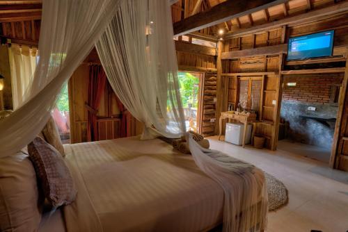 - une chambre avec un lit à baldaquin et une télévision dans l'établissement Sweet Orange Pondok, à Ubud