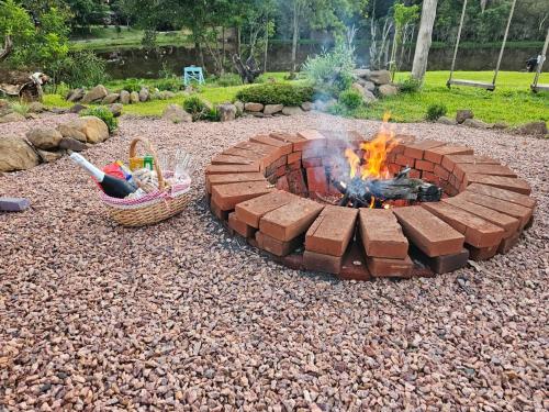 a brick fire pit in a gravel yard with a basket at Cabana Gehrke in Nova Petrópolis