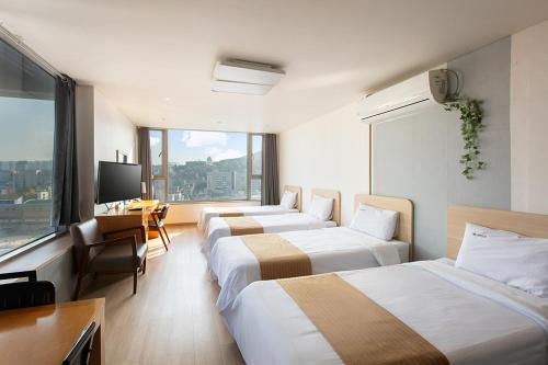 首尔现代住宅的酒店客房设有三张床、一张桌子和一台电视。