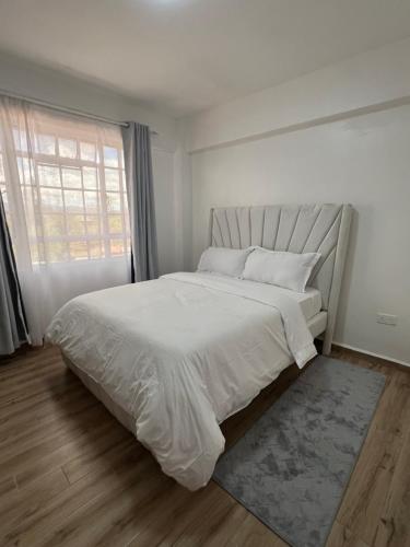 a white bedroom with a large bed and a window at Savannah Residence in Libwezi