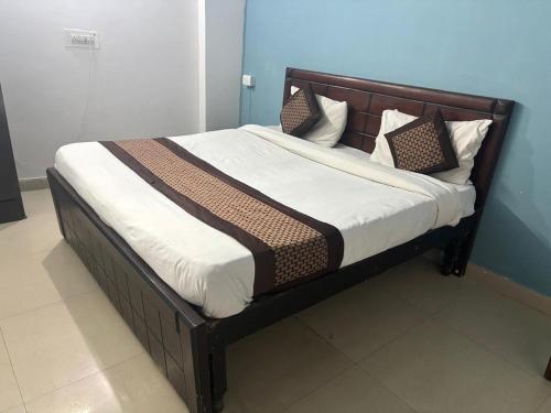 Una cama con marco de madera y almohadas encima. en Hotel R Villa - Near Hauz Khas Fort, en Nueva Delhi