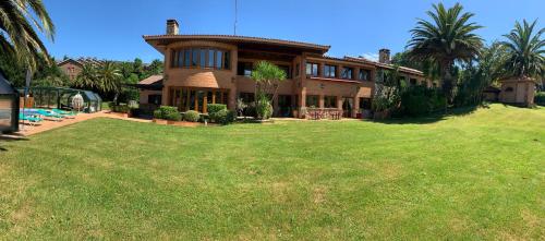 una casa grande con césped delante en Basque Palace, Mansion con Jardín, Barbacoa, Gimnasio, Piscina, Sauna, en Mungia