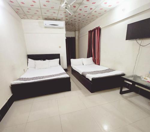 a bedroom with two beds and a television in it at W Hotel Sylhet in Sylhet