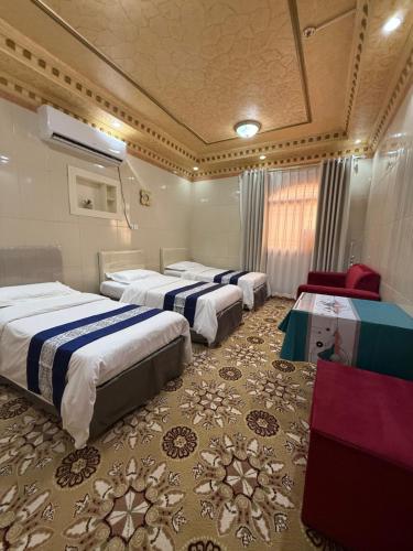 a hotel room with three beds in a room at دار اليقين in Al Madinah