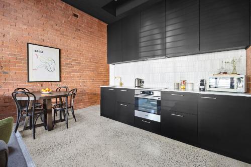 a kitchen with black cabinets and a table with chairs at The Milliner - Boutique Living, Geelong West in Geelong West