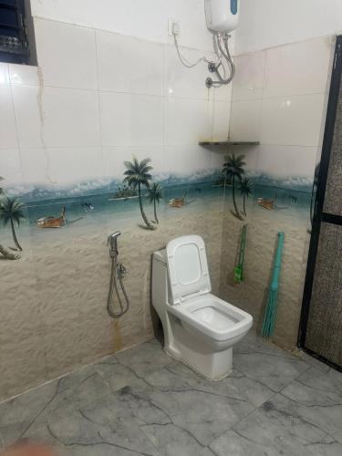 a bathroom with a toilet and palm trees on the wall at water front guest house in Arambol