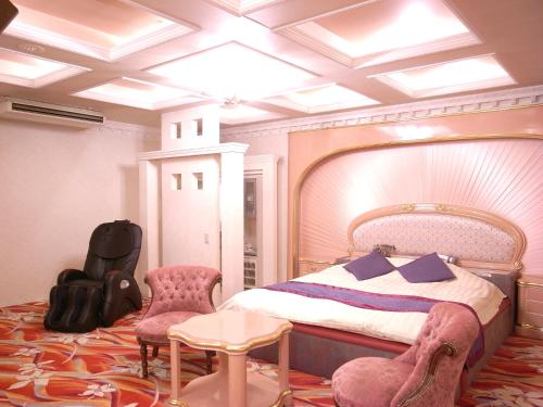 a bedroom with a bed and a table and chairs at ホテル うさぎ -岡山運転免許センター南- in Okayama