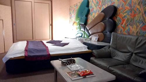 a hotel room with a bed and a couch at ホテル うさぎ -岡山運転免許センター南- in Okayama
