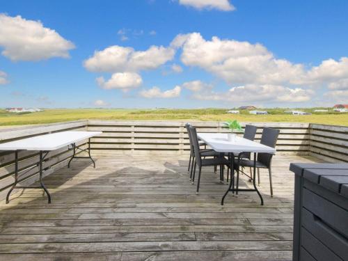 two tables and chairs on a deck with a view of the ocean at 12 person holiday home in Lemvig in Ferring