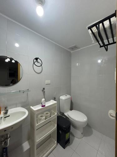 a white bathroom with a toilet and a sink at 2-bedroom unit with Sea & Mountain View in Dumaguete