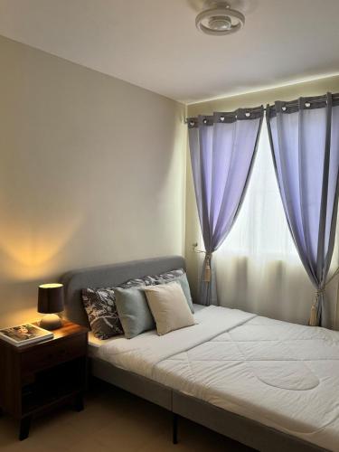 a bedroom with a large bed with purple curtains at 2-bedroom unit with Sea & Mountain View in Dumaguete