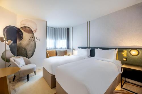 a hotel room with two beds and a chair at Hyatt Centric Reims in Reims