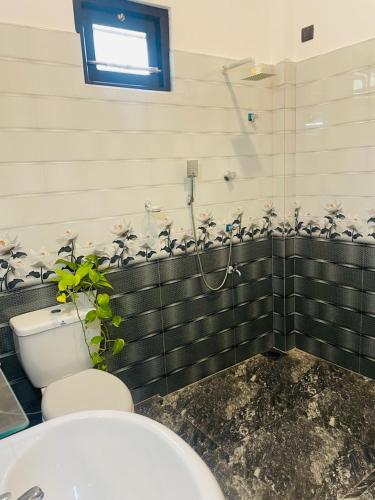 a bathroom with a toilet and a plant in it at Adorable Guest House in Midigama East