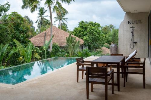 een eettafel en stoelen naast een zwembad bij KUUL Villas in Baan Tai