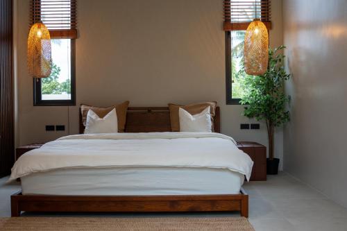 een slaapkamer met een groot wit bed met twee ramen bij KUUL Villas in Baan Tai