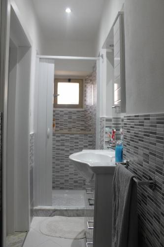Un baño blanco con lavabo y espejo. en Casa Giorgia, en Noto