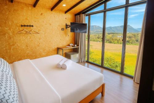 a bedroom with a bed and a large window at ฌานติรีสอร์ท เขาค้อ in Ban Nong Chaeng