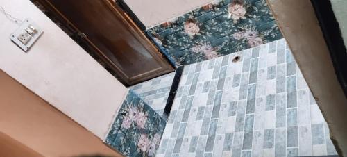a bathroom with a tiled floor and a door at Rk home stay in Jhūsi