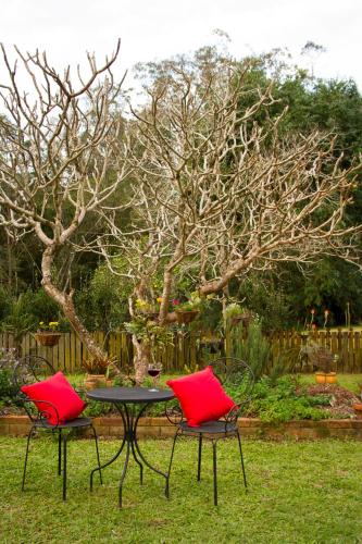two red chairs and a table in a yard at Bielby's Hideaway in Eudlo