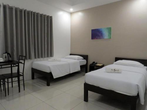 a room with two beds and a table and a desk at Fiesole Residence Inn in Dumaguete