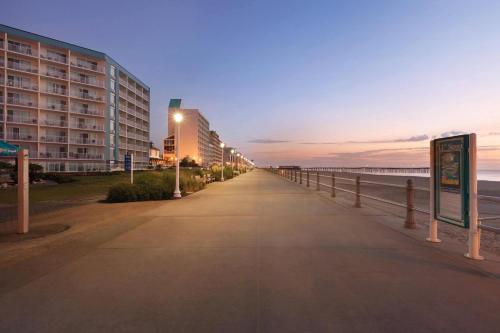 a sidewalk next to a beach with a building at Surfbreak Virginia Beach Oceanfront, an Ascend Collection Hotel in Virginia Beach