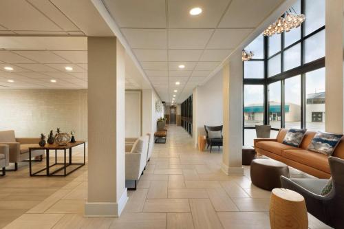 an office lobby with couches and chairs and windows at Surfbreak Virginia Beach Oceanfront, an Ascend Collection Hotel in Virginia Beach
